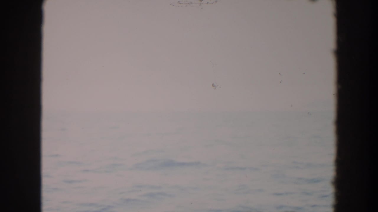 Open water and pale sky divided by a central dark window frame.