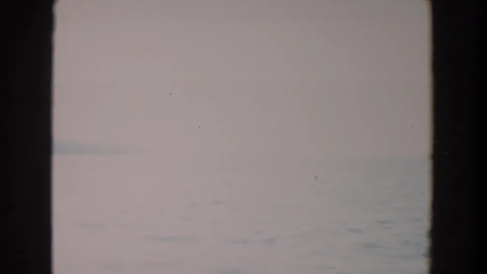 Soft, pale opening frame of water and overcast sky from 1964 Washington home-movie footage, bordered by dark film edges.