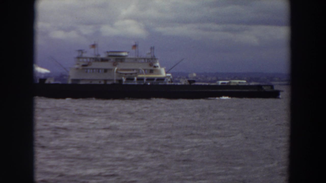Large ferry crossing choppy water beneath a cloudy sky.