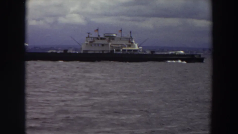 Large ferry continues across a Washington waterway, framed by dark 8mm borders and a cloudy horizon.