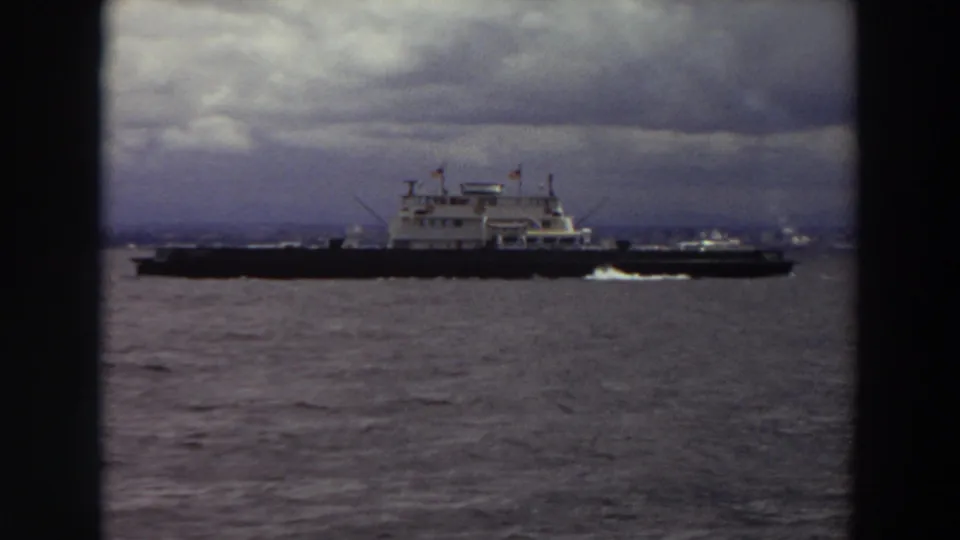 Home-movie view of a large ferry crossing gray water in Washington, with heavy clouds filling the upper frame.