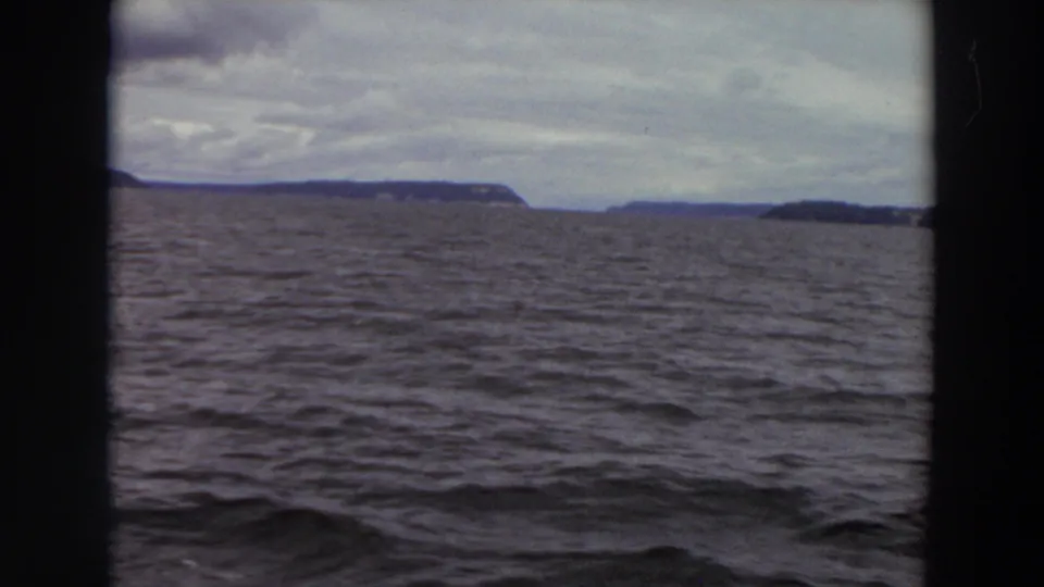Vintage 8mm view of Washington coastal water with low landforms on the horizon and dark gate borders.