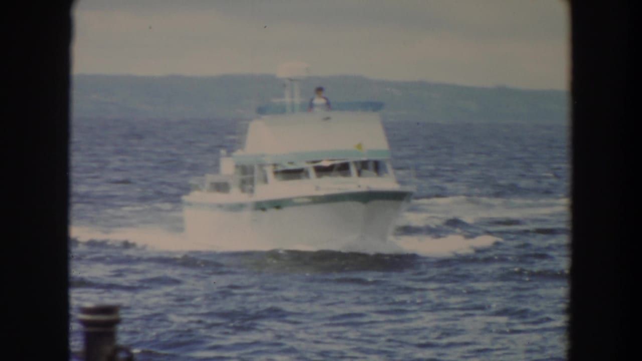 White motor yacht moves across choppy water with a dark frame border at left.
