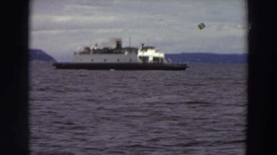 1964 Washington home-movie frame of a ferry on open water, softened by grain and slight exposure variation.