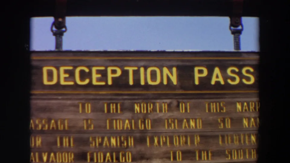 1964 home-movie close-up of the Deception Pass sign, showing the large title and partial text about the narrow passage.