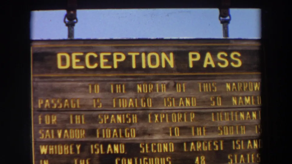 Close-up of a Deception Pass interpretive sign in Washington, with readable lines mentioning Fidalgo Island and Whidbey Island.