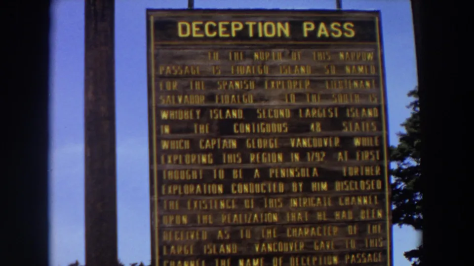 1964 Washington 8mm frame showing a close view of the Deception Pass historical sign, partly cropped by the camera.