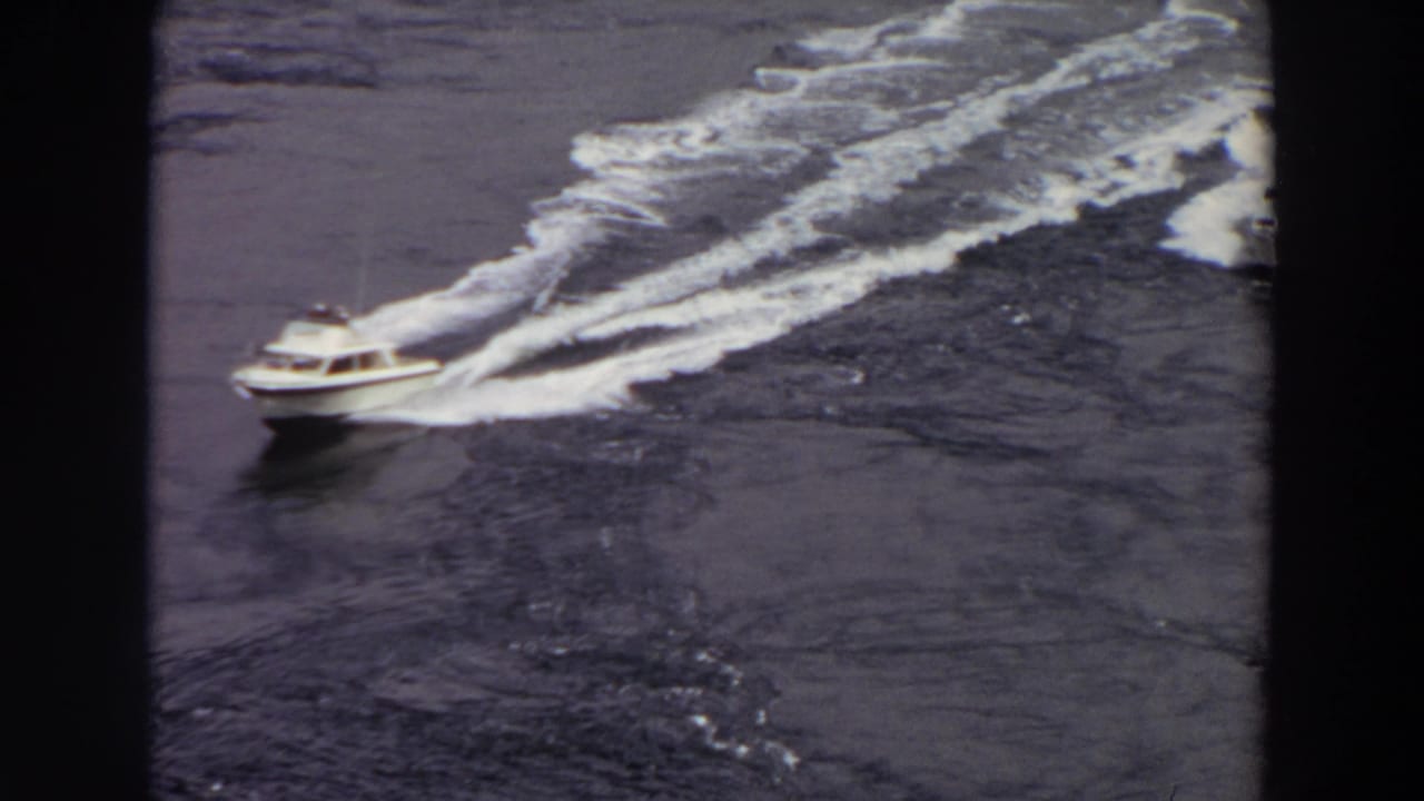 High-angle 8mm view of a white motorboat cutting through Washington waters, with a second boat visible behind it.