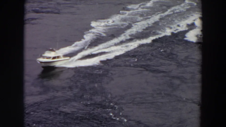 High-angle 8mm view of a white motorboat cutting through Washington waters, with a second boat visible behind it.