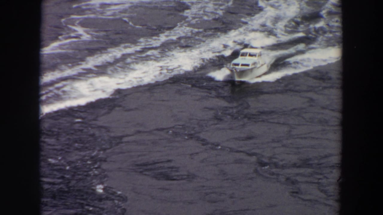 White motorboat moving across dark choppy water with foam behind it.