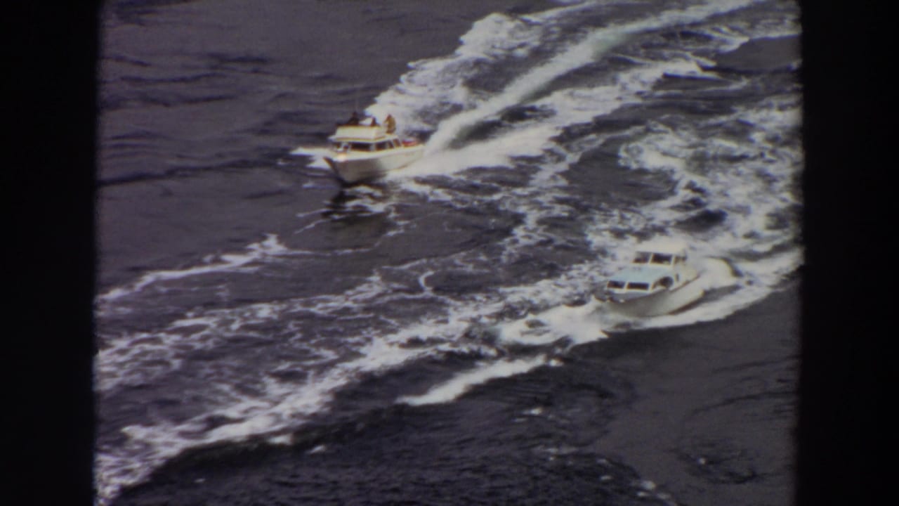 Two white motorboats appear to race across Washington water in 1964 home-movie footage, viewed from above.