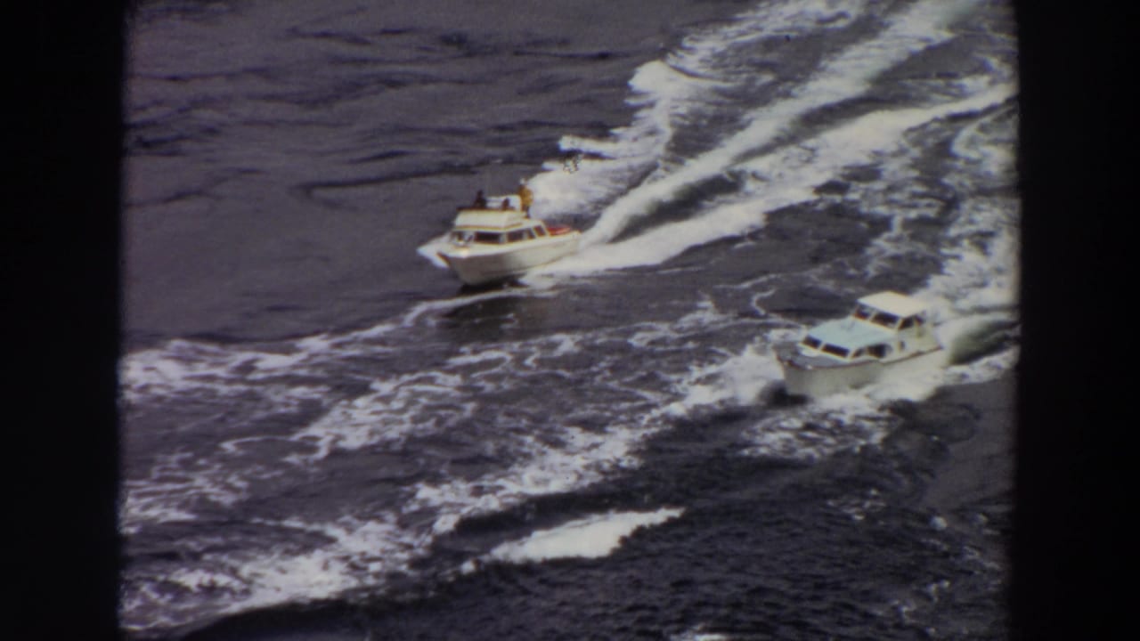 Elevated 8mm view of two recreational motorboats moving through wake-filled water in Washington, 1964.