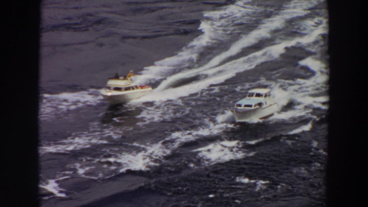 Final frame of two small white motorboats crossing open water, with passengers faintly visible and wakes behind them.