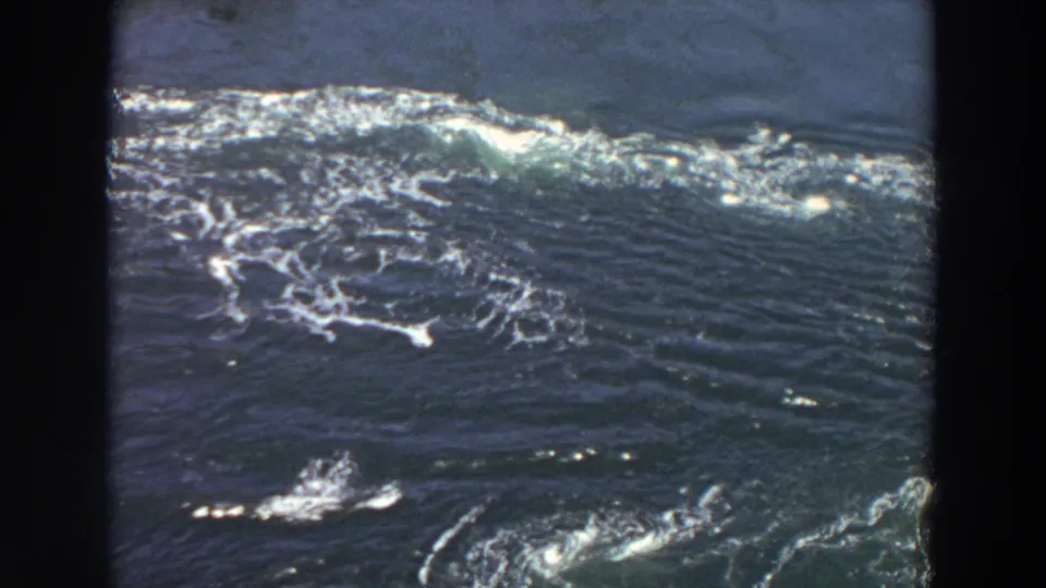 1964 Washington 8mm view of a wide, dark river surface with bright foam bands and visible turbulence across the water.