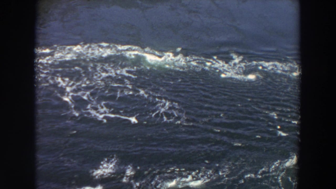1964 Washington home-movie frame showing river rapids, swirling white foam, and dark water within visible 8mm borders.