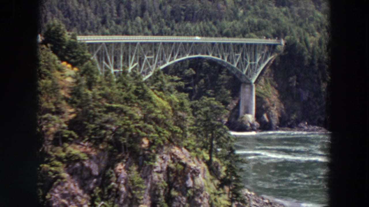 Washington 1964 8mm frame with the bridge centered over moving river water and tree-covered cliffs.