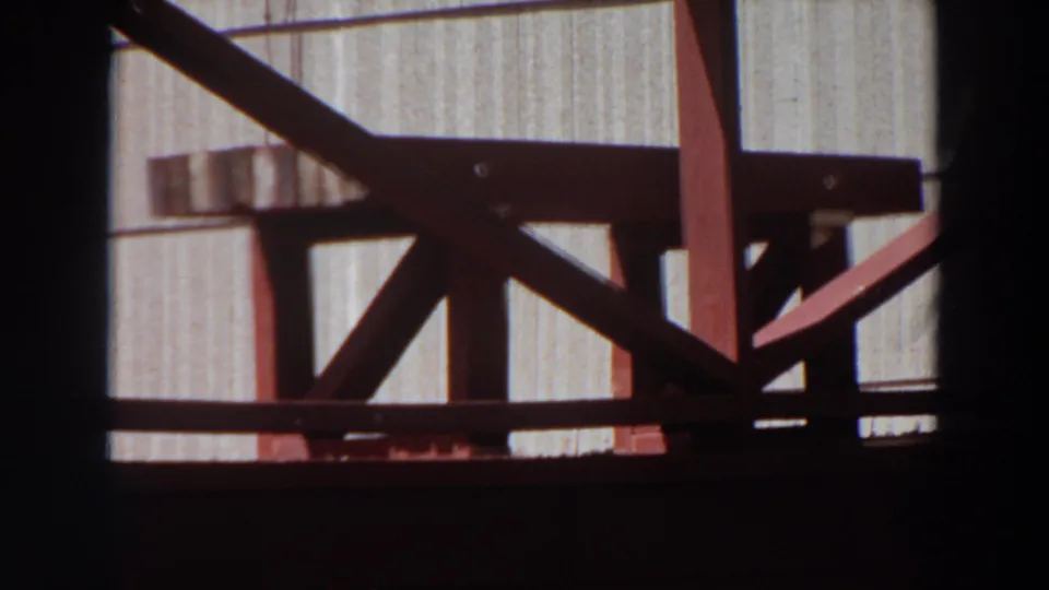 1964 Washington 8mm frame showing a red wooden porch or railing against a light building exterior, with strong shadowing.