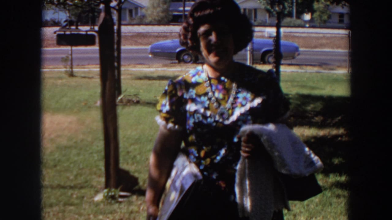 Near the end of the 1964 Washington shot, the woman reaches the foreground while holding a white cloth, with street and parked car behind her.