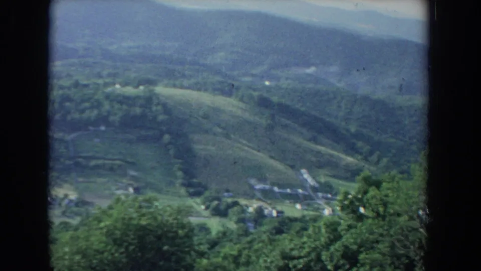 1965 Fallston, Maryland home-movie frame looking across green wooded hills, open fields, and scattered homes from an elevated viewpoint.