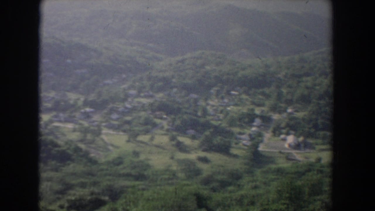 1965 8mm aerial view near Fallston, Maryland, looking across fields, trees, roads, and a small rural settlement.