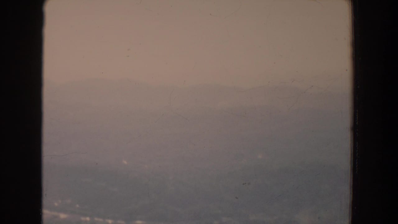 Foggy distant ridge seen through a dark window frame.