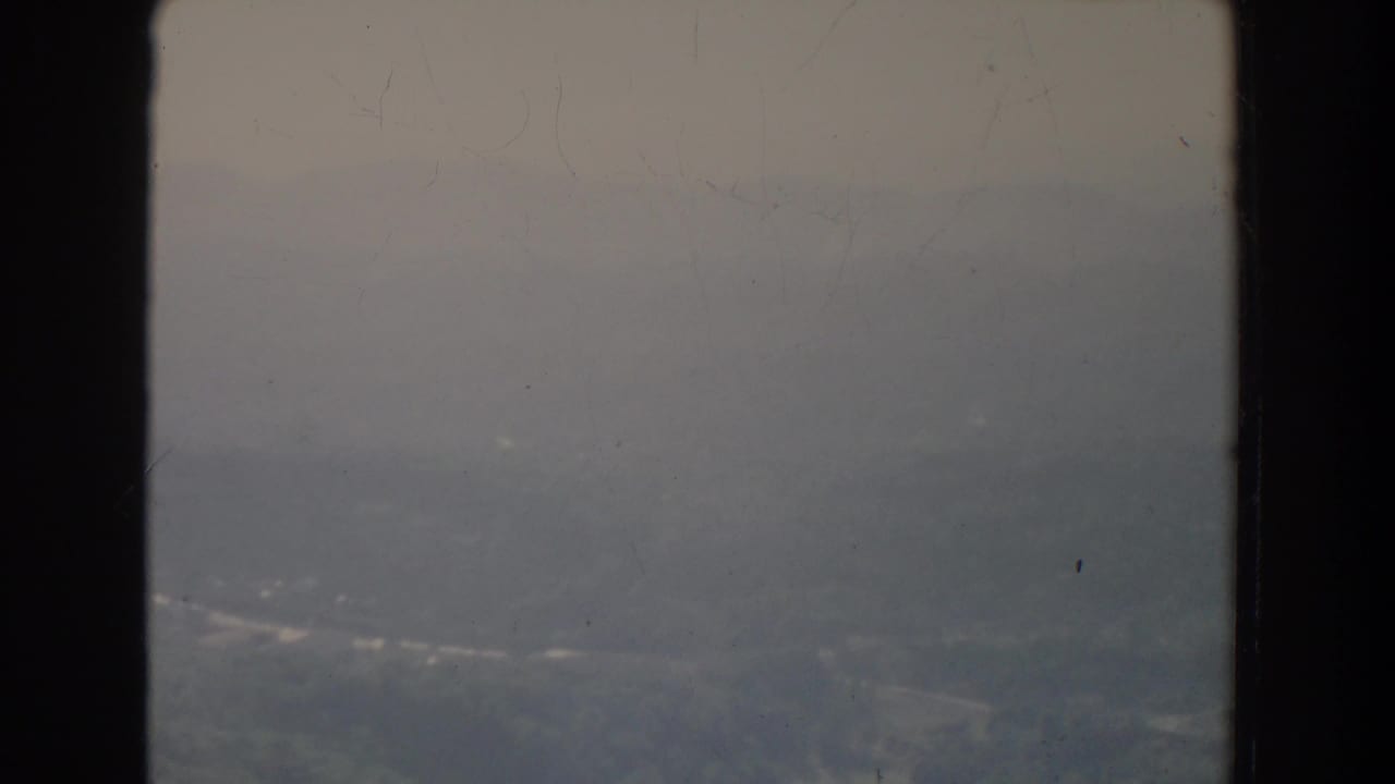 Misty aerial landscape with faint roads beyond a vertical window divider.