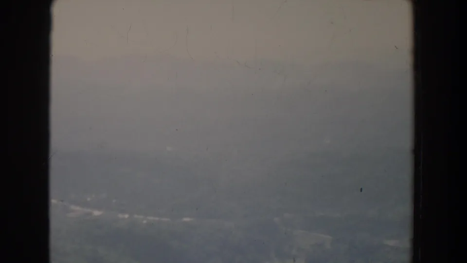 Aerial 8mm view over Fallston, Maryland, with fog-muted hills and faint road traces below.