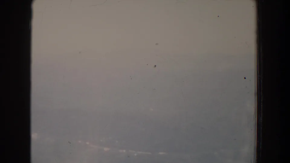 Soft, faded 1965 aerial frame over rural Maryland, showing foggy ground and a barely visible road line.