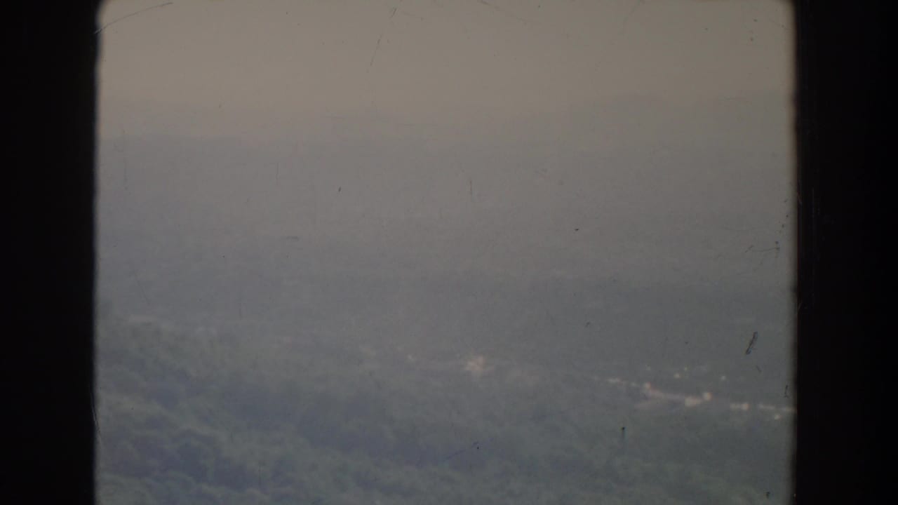 Distant wooded ridge and pale sky with heavy haze and visible film wear.