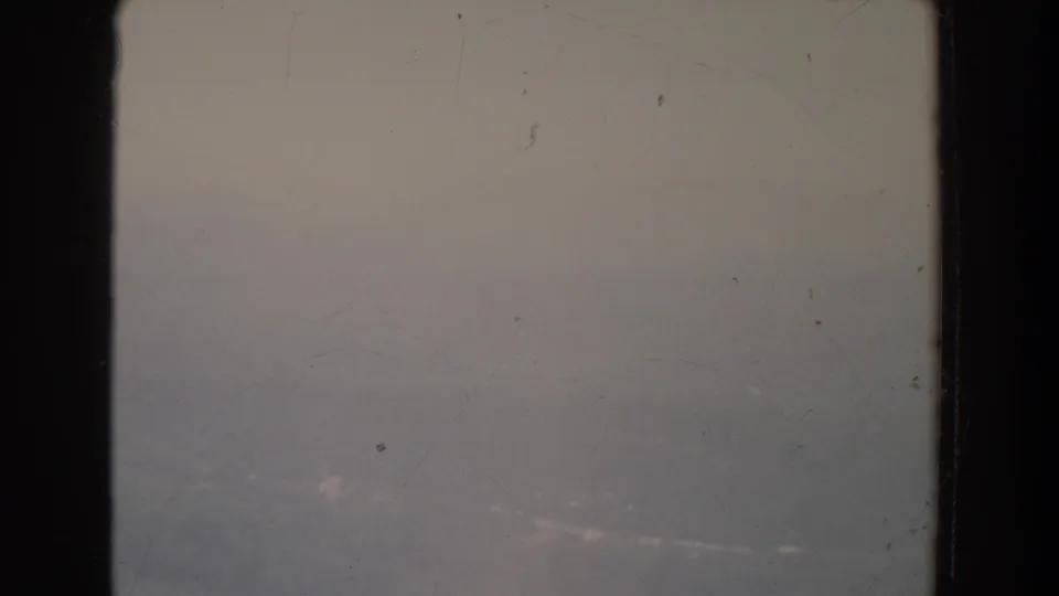 A 1965 8mm home-movie frame from the Fallston, Maryland metadata, showing mostly hazy sky with faint distant terrain and dark frame edges.
