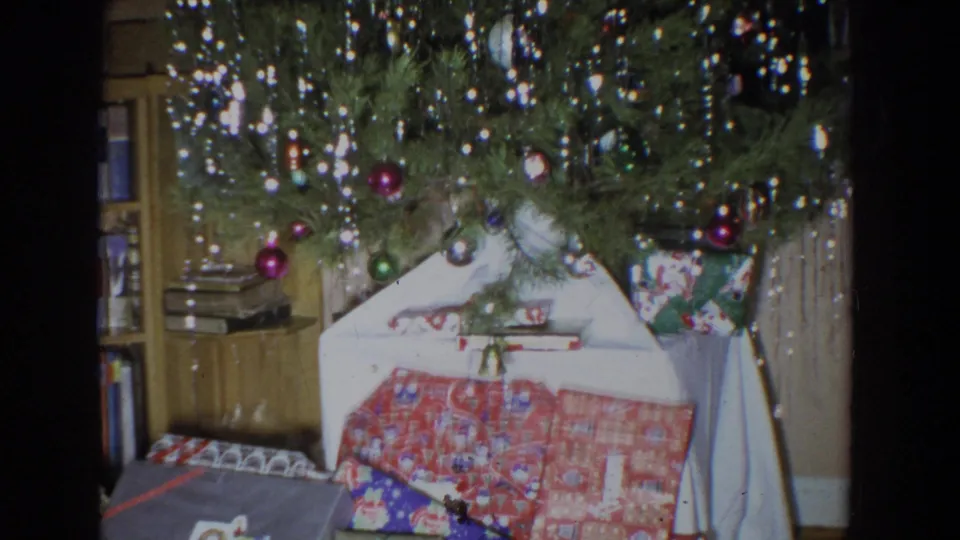 1965 Fallston, Maryland interior with a decorated Christmas tree, tinsel, wrapped gifts, bookshelf, and curtains visible.