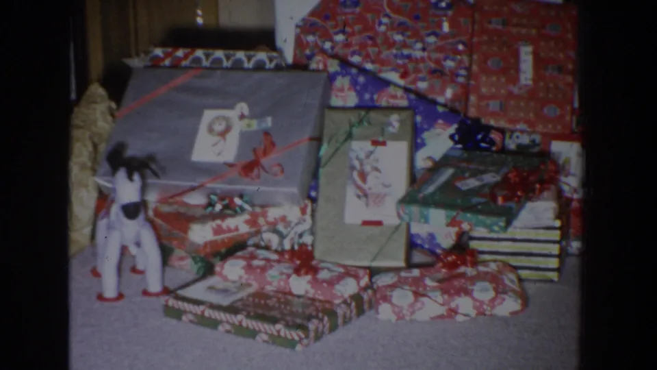 1965 Fallston, Maryland frame showing Christmas packages, a small toy animal figure, bows, and holiday figurines indoors.