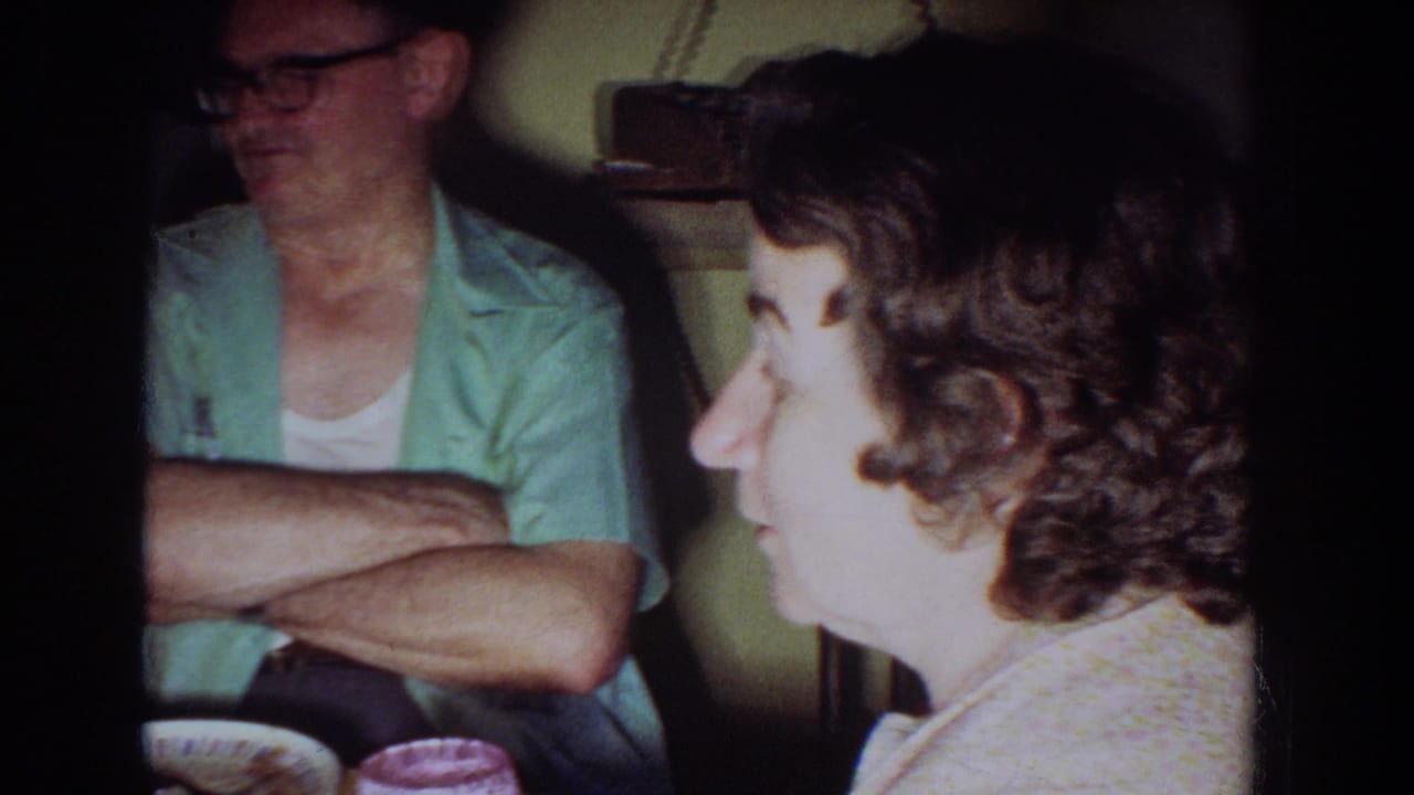 1965 Fallston, Maryland home-movie frame showing adults seated in a kitchen during a casual family conversation.