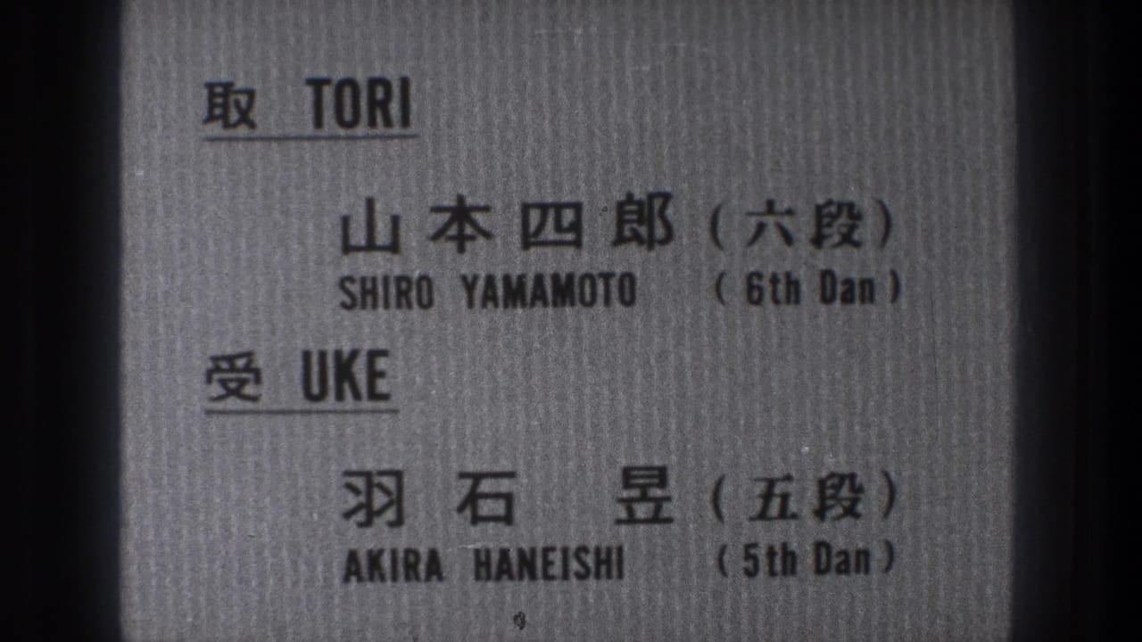 Close 8mm frame of the bilingual martial arts card, with names and dan ranks printed in black.