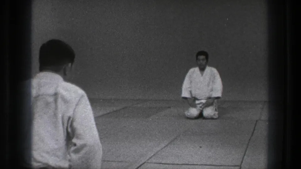 1971 Tokyo 8mm frame showing a martial arts bow, with one man lowered forward and another kneeling opposite him.