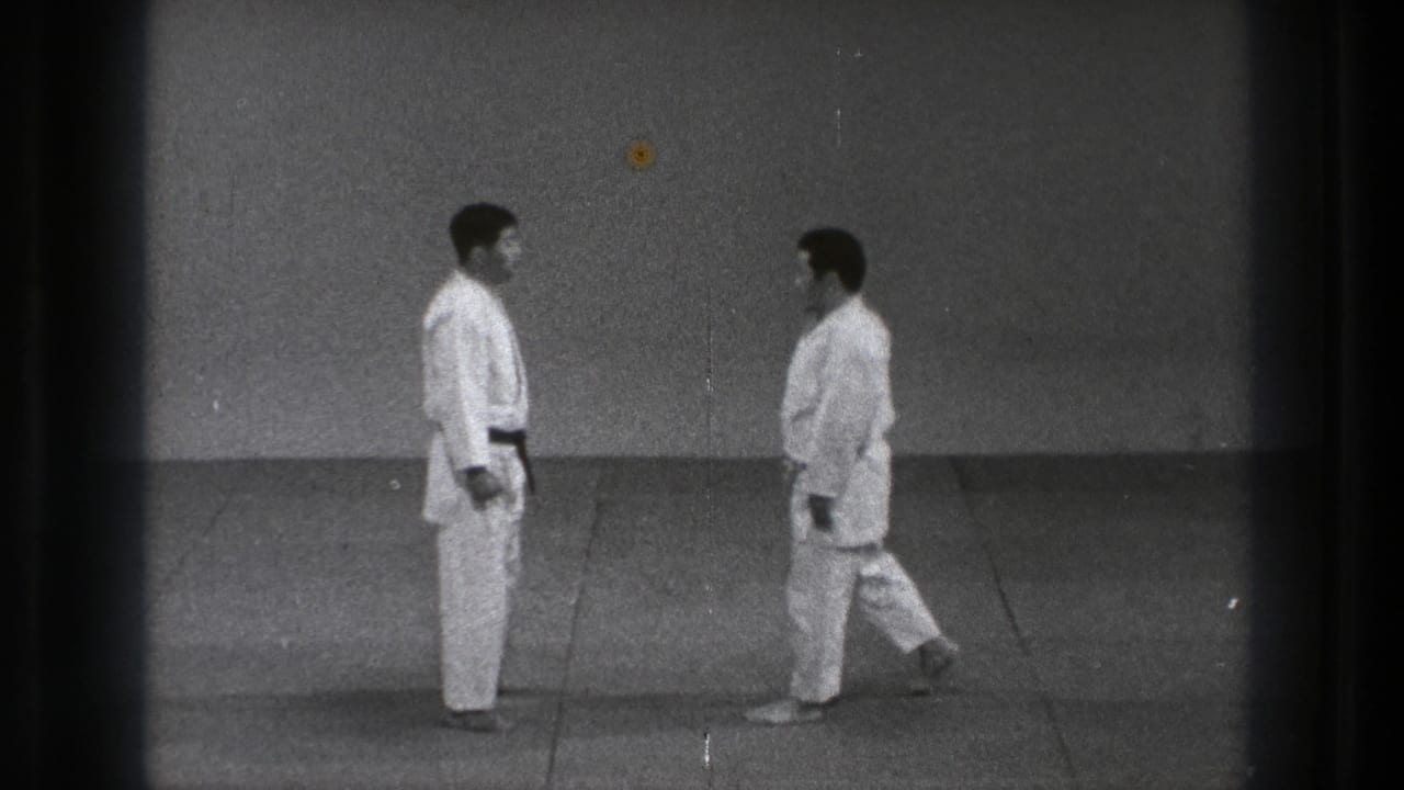 Two men in white martial arts uniforms face each other on a mat.