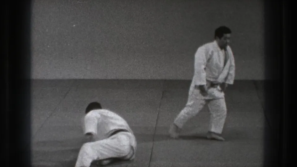 1971 Tokyo martial arts practice with one man low on the mat and another standing in a white gi at a distance.