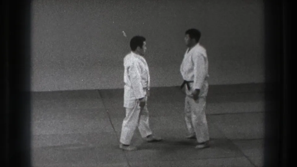 1971 Tokyo judo demonstration frame with two adults in white gi facing each other, one wearing a dark belt.