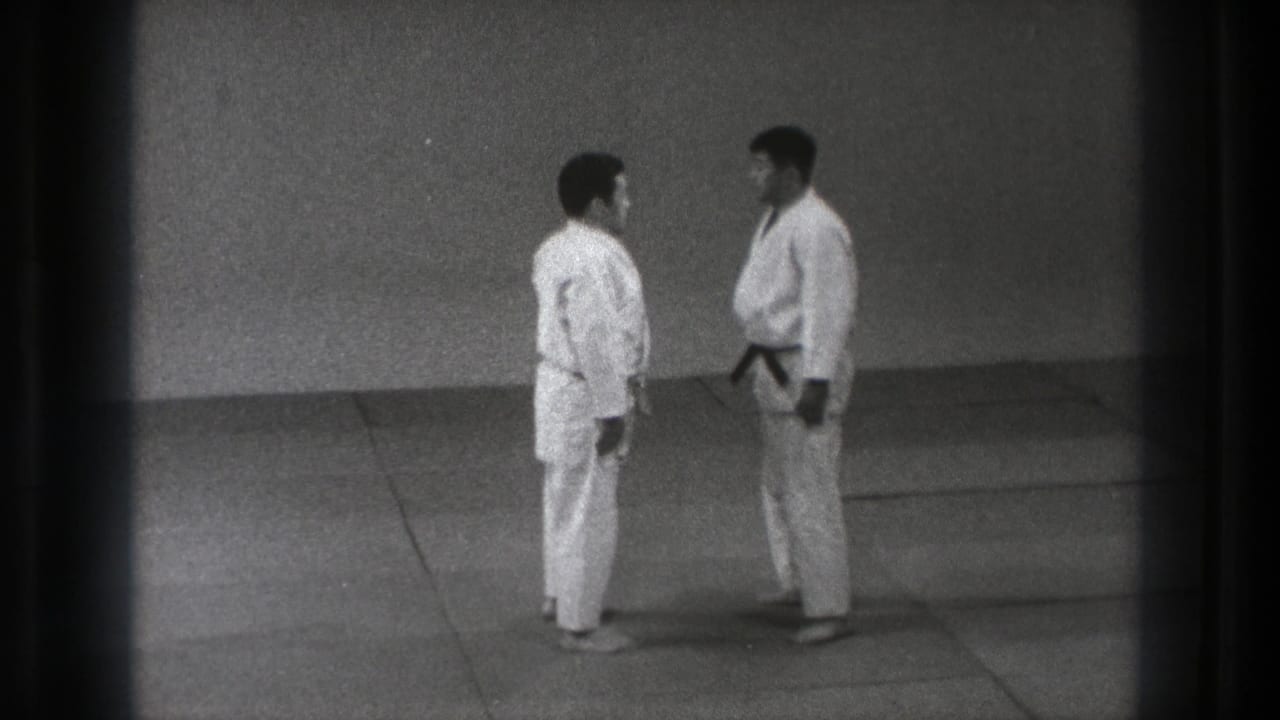 1971 Tokyo dojo frame showing two judo practitioners in gi standing close on the mat before a demonstration grip.