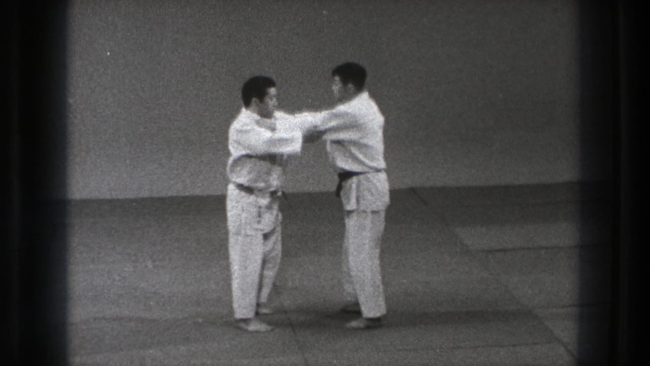 Two men in white judo uniforms face each other on a mat.