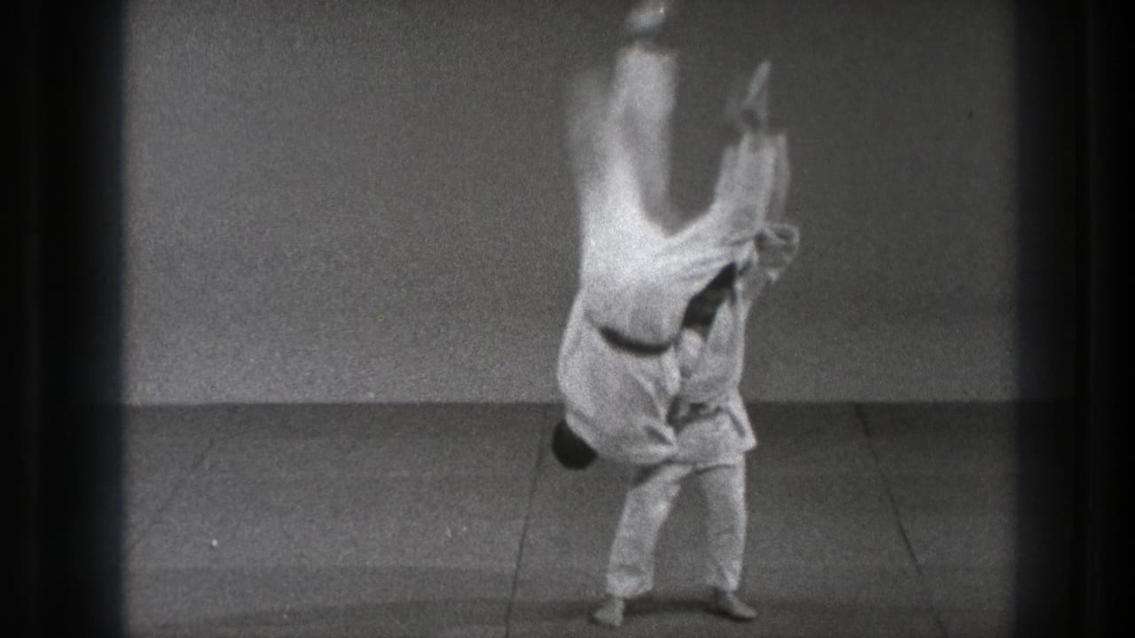 Two men in white gi during a martial arts throw on a mat.