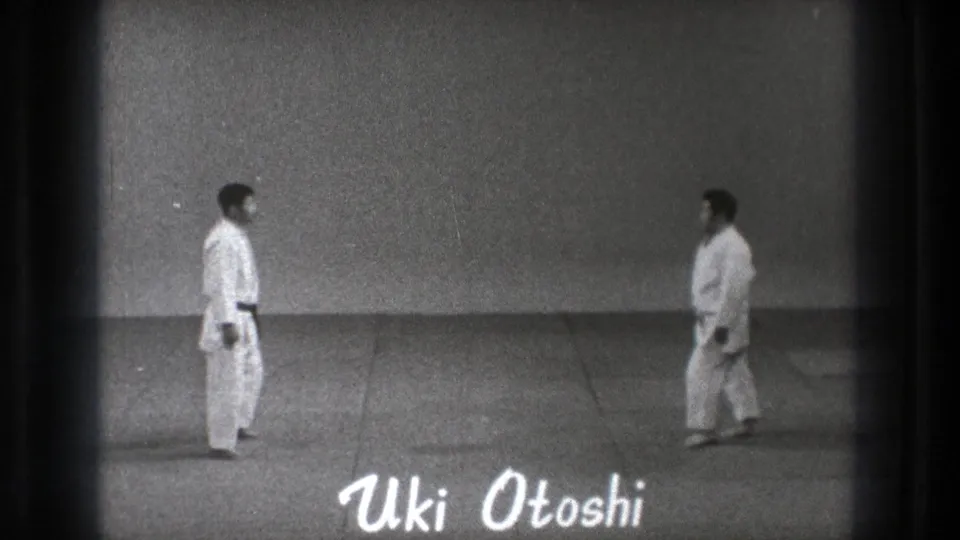 Black-and-white 1971 Tokyo frame showing two martial arts practitioners on a mat with the text Uki Otoshi overlaid near the bottom.