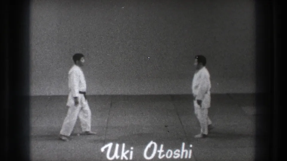 In 1971 Tokyo judo footage, two men in white judogi face each other across a mat as the title Uki Otoshi appears over the frame.