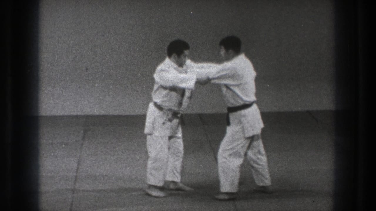 The practitioners close distance during the karate or grappling drill, with both men leaning into the exchange on the mat.