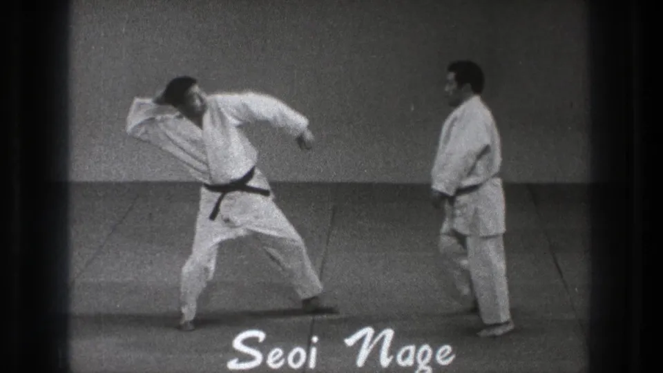 1971 Tokyo training footage shows two adult men in white martial-arts gi, with one black-belt practitioner starting a Seoi Nage demonstration.