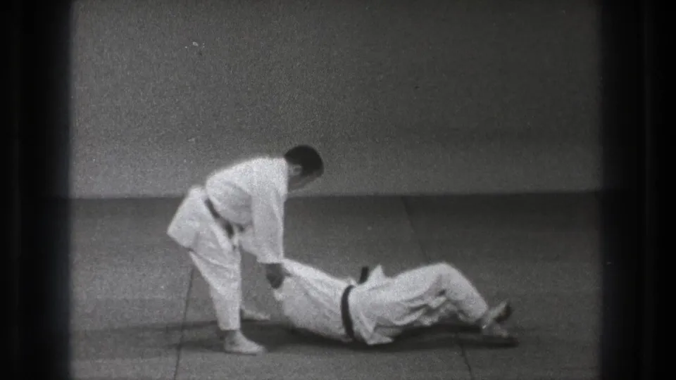 A karate practitioner stands over his partner on the mat during a controlled follow-through in the 1971 Tokyo demonstration.