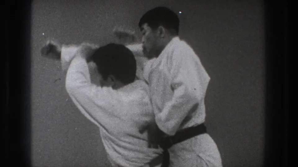 In the Tokyo 1971 clip, one practitioner bends under an arm as the other controls the movement during the throw.