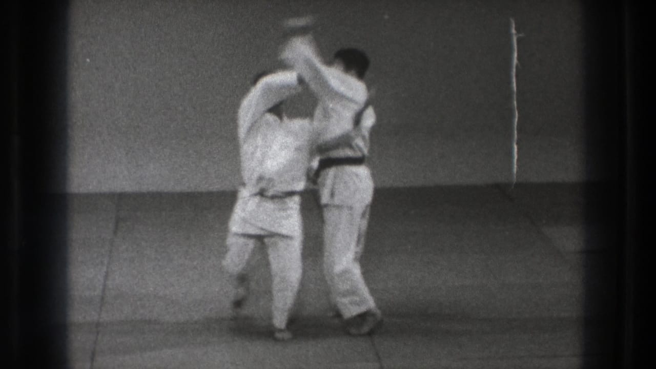 Two karate practitioners make upper-body contact during a blocking move.