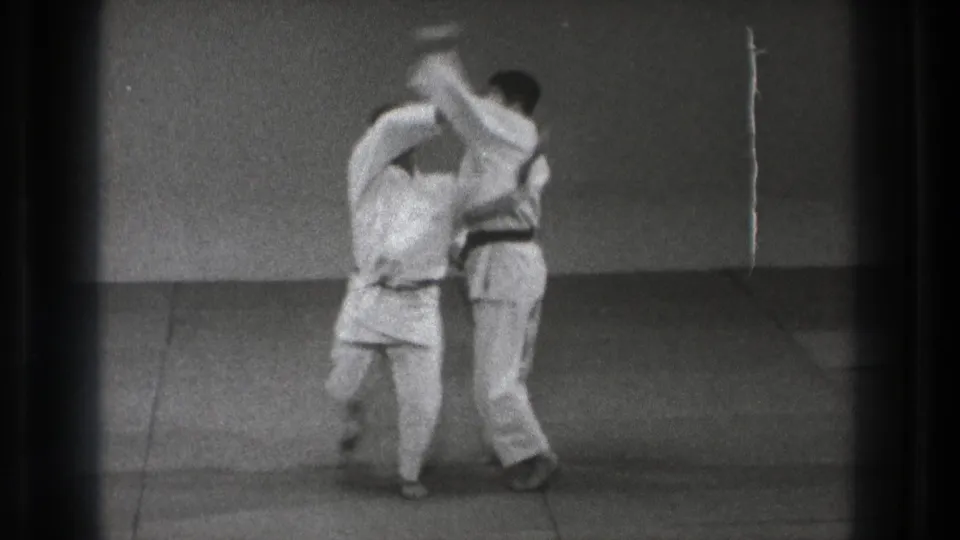 Two men in white gi practice a close blocking or disarm movement during a 1971 Tokyo karate training sequence.