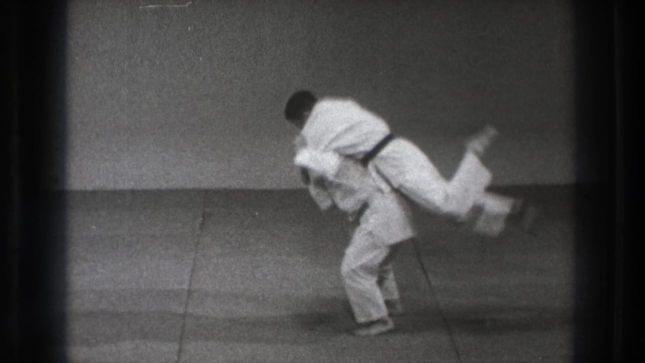 Two martial artists in white gi begin a judo throw on a mat.